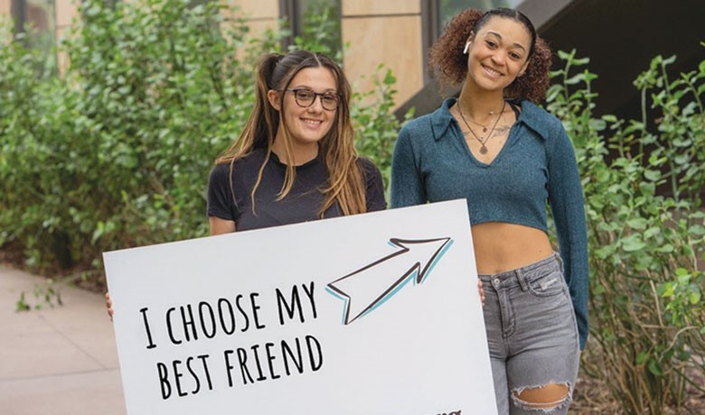 Two college students carrying a sign