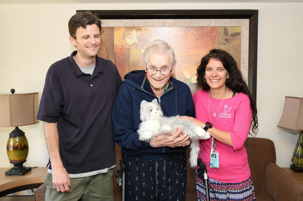 Volunteer Andrew Gaines (left) and social worker Michelle Bales visit with patient Walter “Wally” Brown and his mechanical cat.